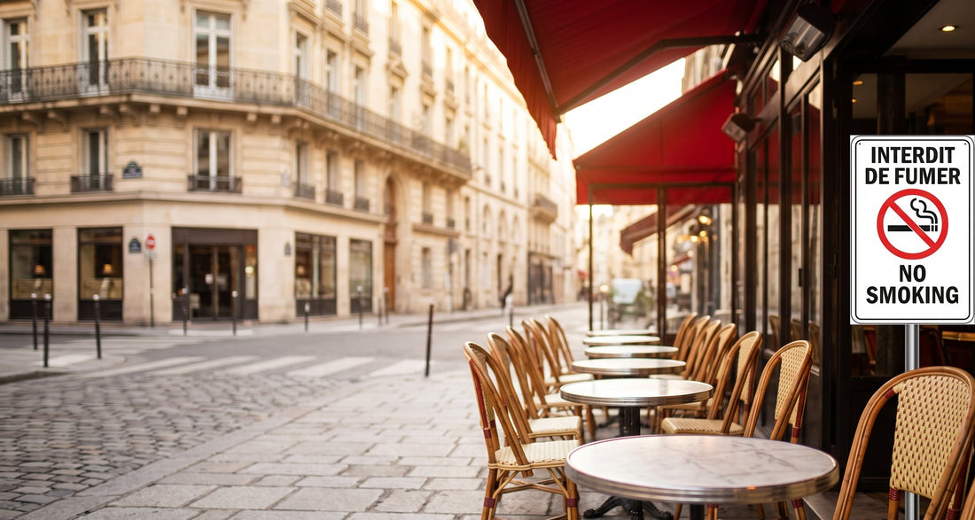 Terrasse de café parisien avec panneau interdiction de fumer et chaises bistrot