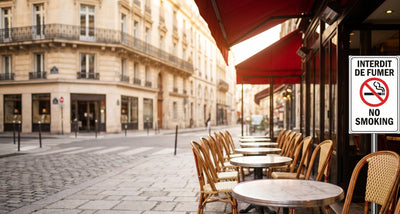 Terrasse de café parisien avec panneau interdiction de fumer et chaises bistrot